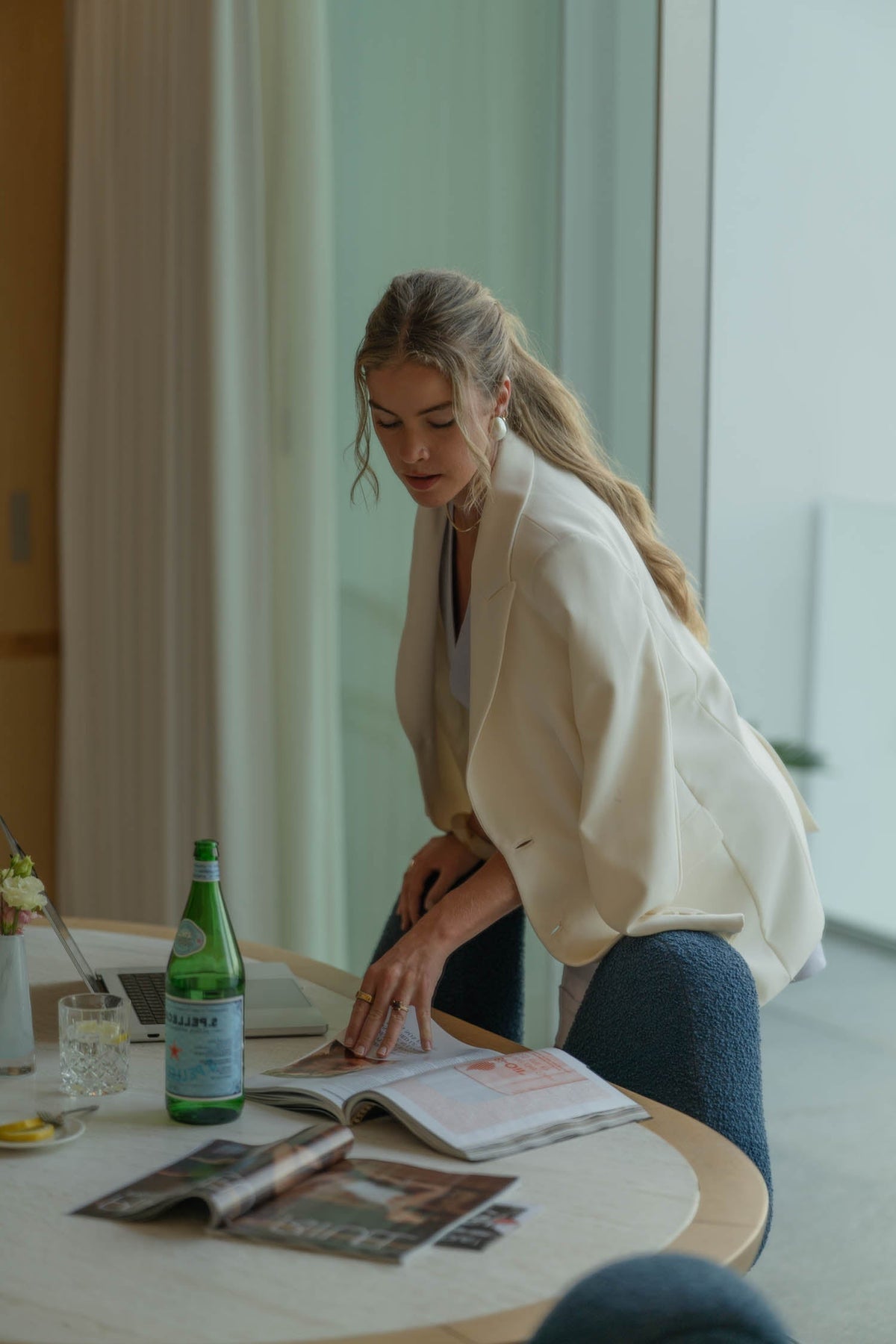 Working mother/mom in a cream blazer standing over her laptop in a bright office